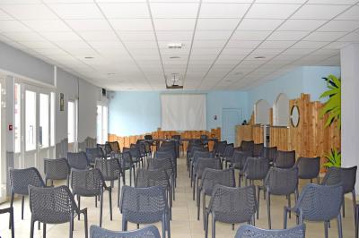 Piscine extérieure avec toboggans, jets d'eau et chaises colorées disposées autour sous un ciel dégagé.