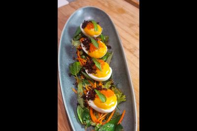 Assiette gastronomique avec saumon, mousse blanche, herbes fraîches et sauce jaune décorée de points verts.