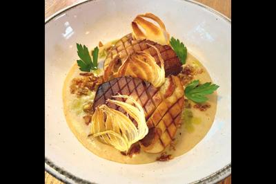 Assiette gastronomique avec saumon, mousse blanche, herbes fraîches et sauce jaune décorée de points verts.