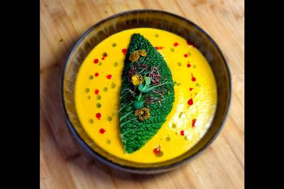 Assiette gastronomique avec saumon, mousse blanche, herbes fraîches et sauce jaune décorée de points verts.