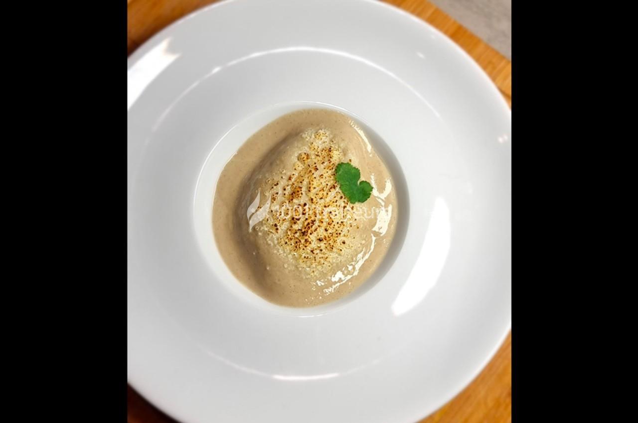 Purée crémeuse servie dans une assiette blanche, garnie d'une feuille de coriandre et légèrement grillée.