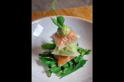 Assiette gastronomique avec saumon, mousse blanche, herbes fraîches et sauce jaune décorée de points verts.