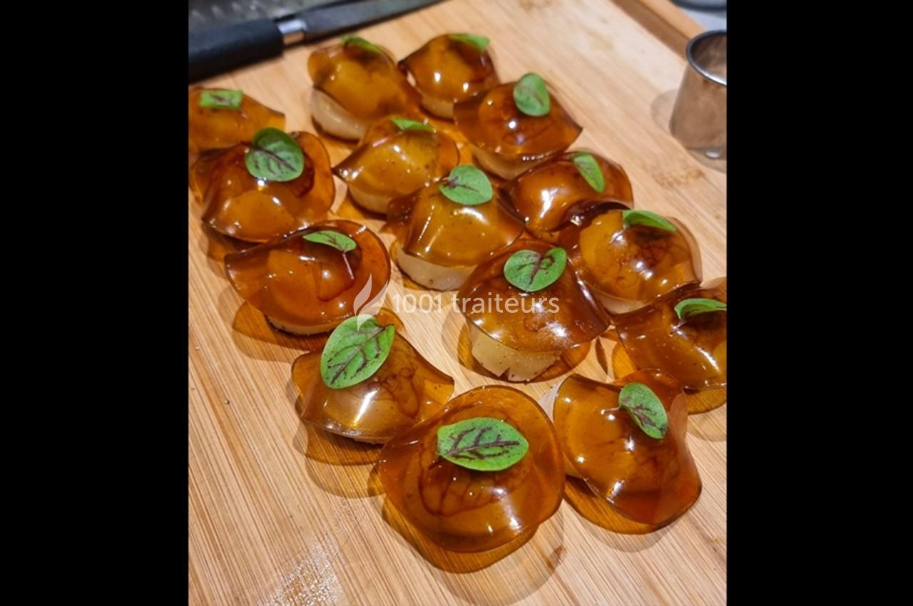 Petites bouchées translucides garnies de feuilles vertes, disposées sur une planche en bois.