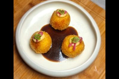 Assiette gastronomique avec saumon, mousse blanche, herbes fraîches et sauce jaune décorée de points verts.