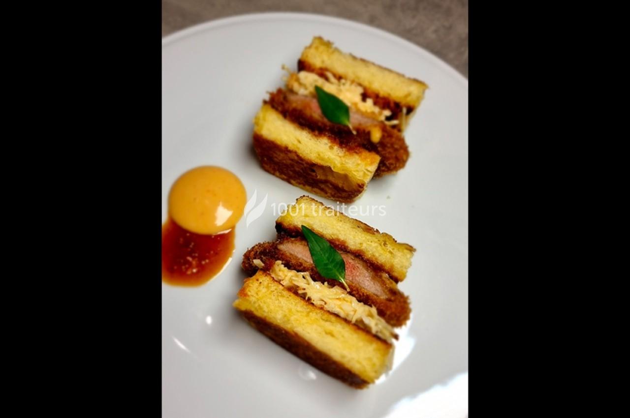 Deux portions de sandwichs frits garnis de viande et de sauce, accompagnées d'une sauce en cercle sur une assiette blanche.