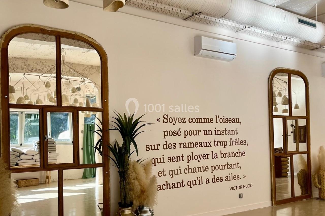 Salle lumineuse avec miroirs, plantes, décorations naturelles et une citation de Victor Hugo inscrite sur le mur.