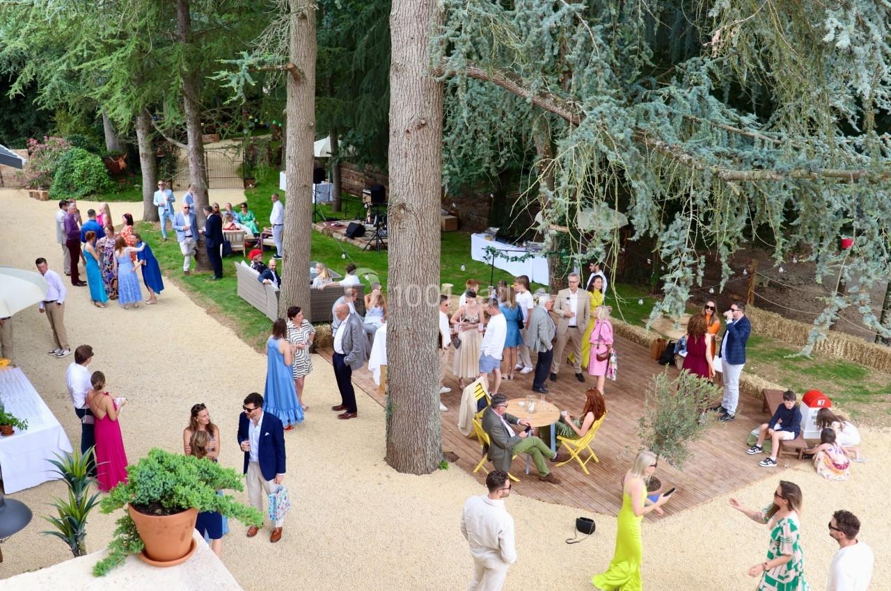 Groupe de personnes rassemblées dans un jardin, discutant et profitant d'un événement en plein air.