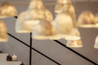 Terrasse en bois aménagée avec des fauteuils, coussins et poufs, entourée d'arbres dans un cadre naturel.