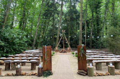 Terrasse en bois aménagée avec des fauteuils, coussins et poufs, entourée d'arbres dans un cadre naturel.