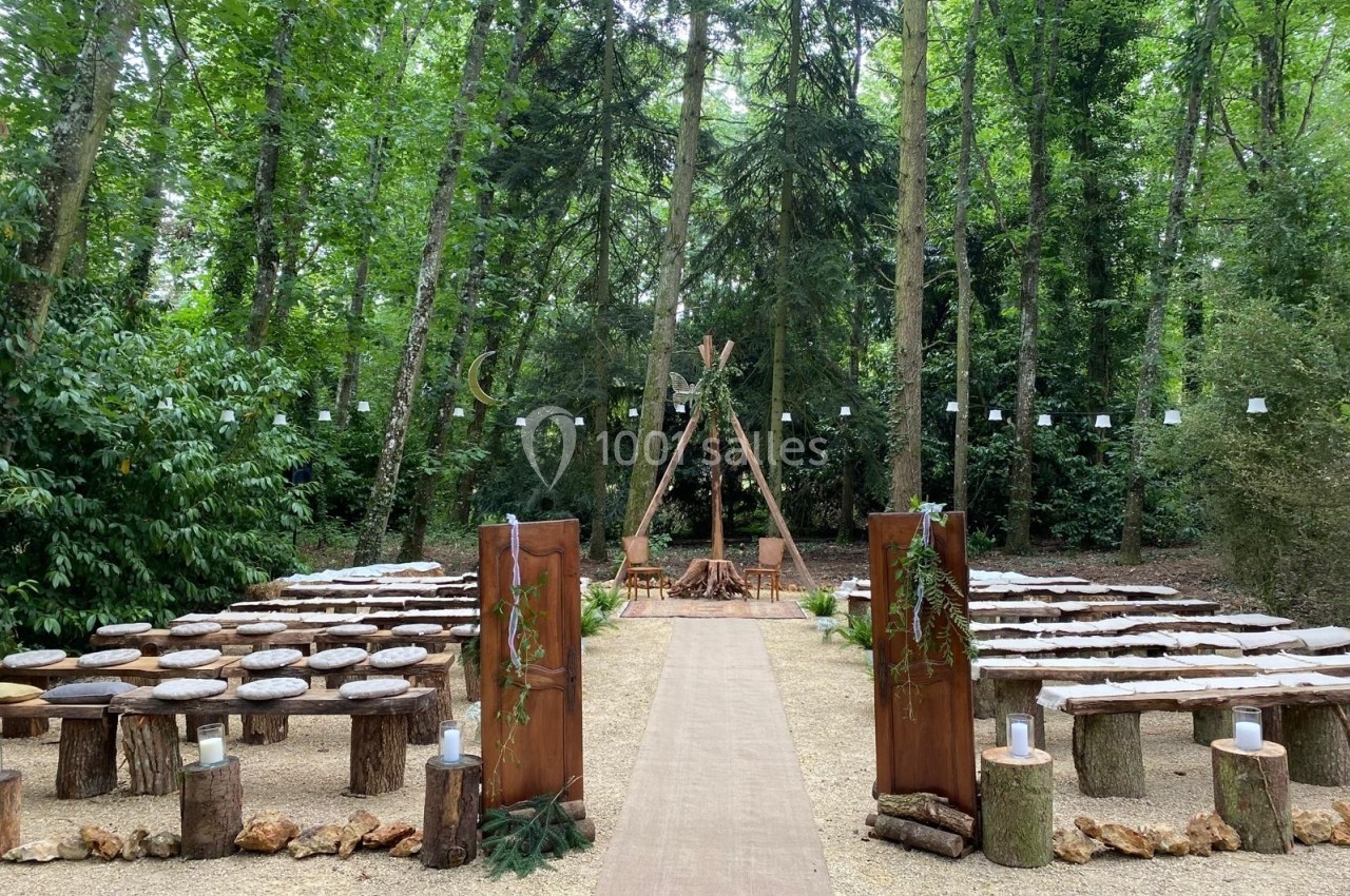 Allée centrale menant à un espace de cérémonie en plein air, entouré de bancs en bois et décoré de végétation.