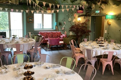 Terrasse en bois aménagée avec des fauteuils, coussins et poufs, entourée d'arbres dans un cadre naturel.