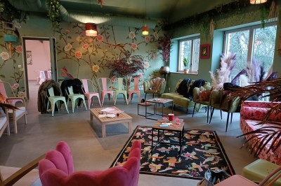 Terrasse en bois aménagée avec des fauteuils, coussins et poufs, entourée d'arbres dans un cadre naturel.