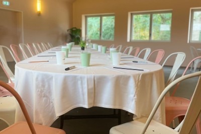 Terrasse en bois aménagée avec des fauteuils, coussins et poufs, entourée d'arbres dans un cadre naturel.