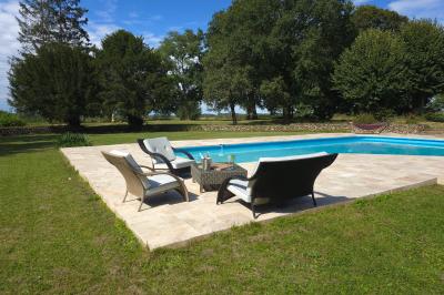 Tables dressées avec nappes blanches et décoration florale sur une terrasse ensoleillée, avec des convives en arrière-plan.