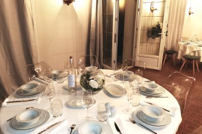 Tables dressées avec nappes blanches et décoration florale sur une terrasse ensoleillée, avec des convives en arrière-plan.