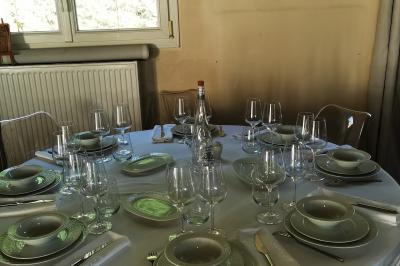 Tables dressées avec nappes blanches et décoration florale sur une terrasse ensoleillée, avec des convives en arrière-plan.