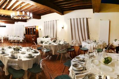 Tables dressées avec nappes blanches et décoration florale sur une terrasse ensoleillée, avec des convives en arrière-plan.