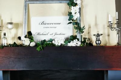 Tables dressées avec nappes blanches et décoration florale sur une terrasse ensoleillée, avec des convives en arrière-plan.