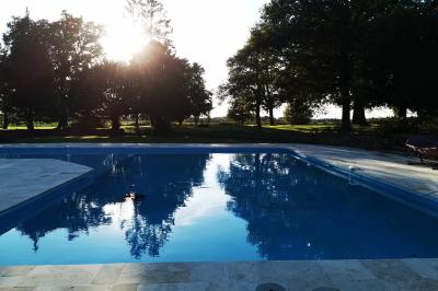 Tables dressées avec nappes blanches et décoration florale sur une terrasse ensoleillée, avec des convives en arrière-plan.