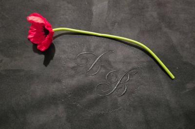 Tables dressées avec nappes blanches et décoration florale sur une terrasse ensoleillée, avec des convives en arrière-plan.