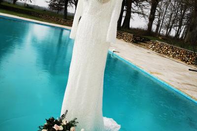 Tables dressées avec nappes blanches et décoration florale sur une terrasse ensoleillée, avec des convives en arrière-plan.