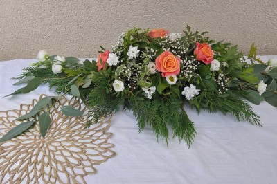 Tables dressées avec nappes blanches et décoration florale sur une terrasse ensoleillée, avec des convives en arrière-plan.