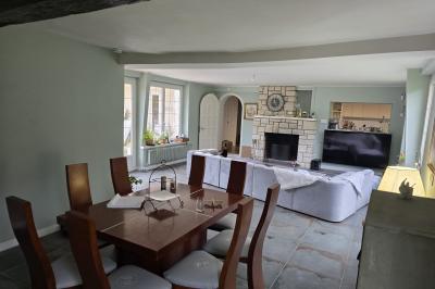 Tables dressées avec nappes blanches et décoration florale sur une terrasse ensoleillée, avec des convives en arrière-plan.