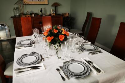 Tables dressées avec nappes blanches et décoration florale sur une terrasse ensoleillée, avec des convives en arrière-plan.