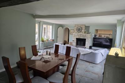 Piscine extérieure bordée de dalles, devant une grande maison traditionnelle avec toit en tuiles rouges.