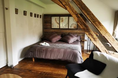 Piscine extérieure bordée de dalles, devant une grande maison traditionnelle avec toit en tuiles rouges.