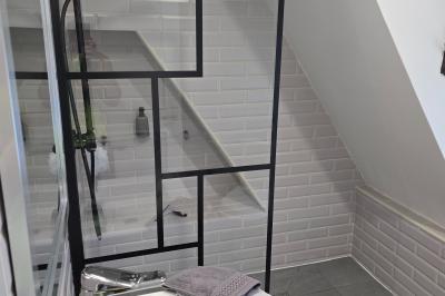 Piscine extérieure bordée de dalles, devant une grande maison traditionnelle avec toit en tuiles rouges.