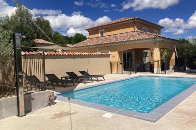 Vue d'une table avec croissants et fruits, devant une porte ouverte sur une terrasse avec piscine et paysage verdoyant.