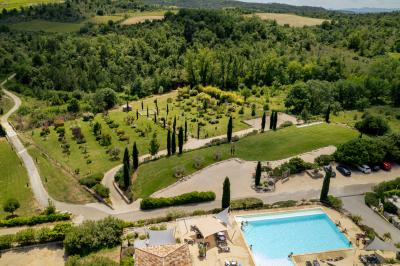 Vue d'une table avec croissants et fruits, devant une porte ouverte sur une terrasse avec piscine et paysage verdoyant.