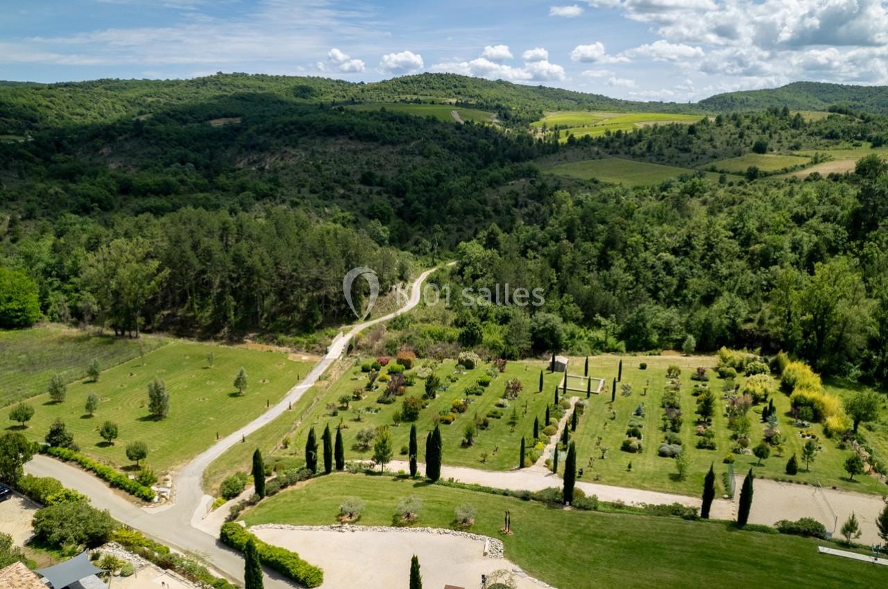 Vue aérienne d'un paysage vallonné avec des chemins sinueux, des arbres et des espaces verts aménagés.
