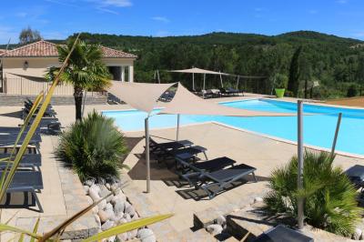 Vue d'une table avec croissants et fruits, devant une porte ouverte sur une terrasse avec piscine et paysage verdoyant.