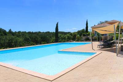 Vue d'une table avec croissants et fruits, devant une porte ouverte sur une terrasse avec piscine et paysage verdoyant.