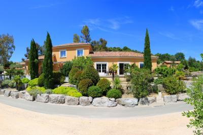 Vue d'une table avec croissants et fruits, devant une porte ouverte sur une terrasse avec piscine et paysage verdoyant.