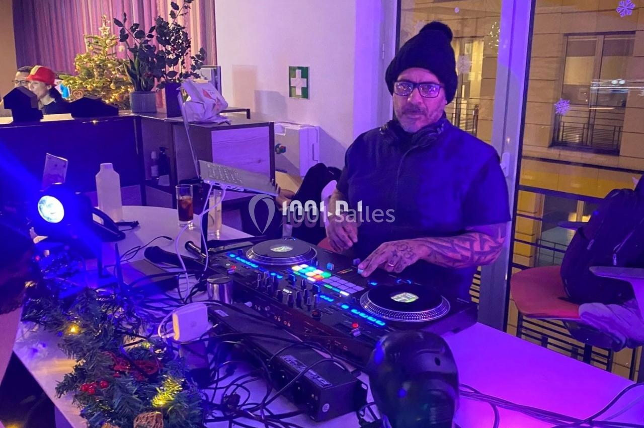 Un DJ portant un bonnet mixe de la musique sur une table de mixage dans un espace décoré pour les fêtes.