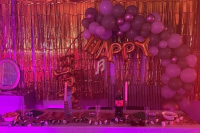 Texte écrit sur un miroir entouré d'une lumière rose, avec des décorations dorées et une table en arrière-plan.