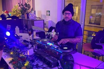 Un DJ portant un bonnet mixe de la musique sur une table de mixage dans un espace décoré pour les fêtes.
