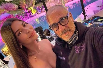 Un homme et une femme posent devant une table de mixage près d'une piscine éclairée en soirée.