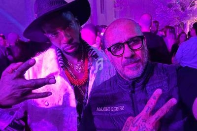 Deux hommes posent ensemble dans un environnement festif avec un éclairage violet.