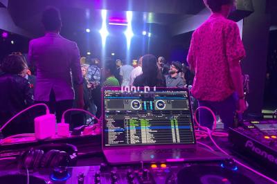 Un DJ portant un bonnet mixe de la musique sur une table de mixage dans un espace décoré pour les fêtes.