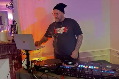 Un DJ portant un bonnet mixe de la musique sur une table de mixage dans un espace décoré pour les fêtes.