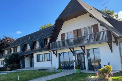 Baby-foot en bois clair avec pieds noirs, situé dans une pièce au sol sombre et murs clairs avec une porte grise.