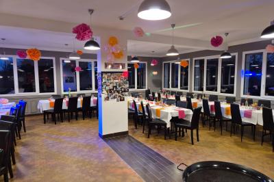 Baby-foot en bois clair avec pieds noirs, situé dans une pièce au sol sombre et murs clairs avec une porte grise.