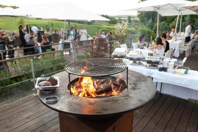 Salle de restaurant lumineuse avec tables rondes dressées, chaises marron et grandes baies vitrées.
