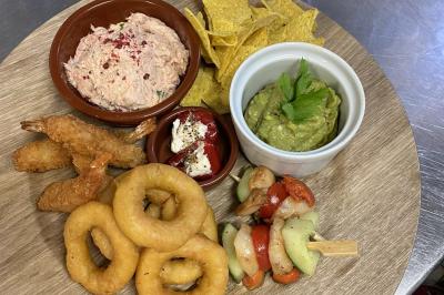 Brochettes de viande et légumes colorés disposées sur des plateaux en cuisine, avec des légumes frais en arrière-plan.