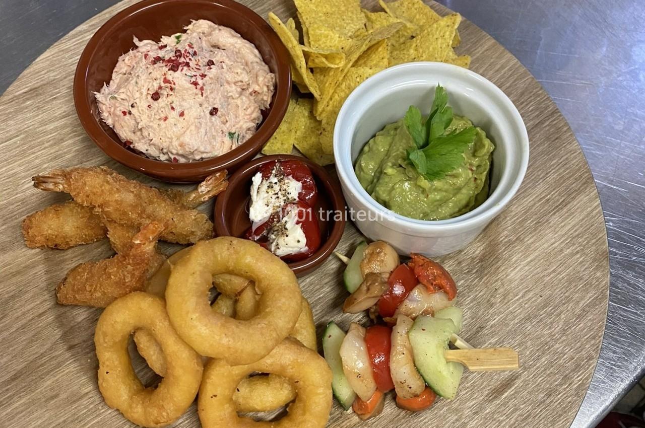 Assortiment d'amuse-bouches avec guacamole, rillettes, crevettes panées, beignets d'oignon et brochettes de légumes.