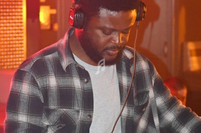 Un homme portant un casque audio mixe de la musique sur une table de mixage dans un environnement éclairé.